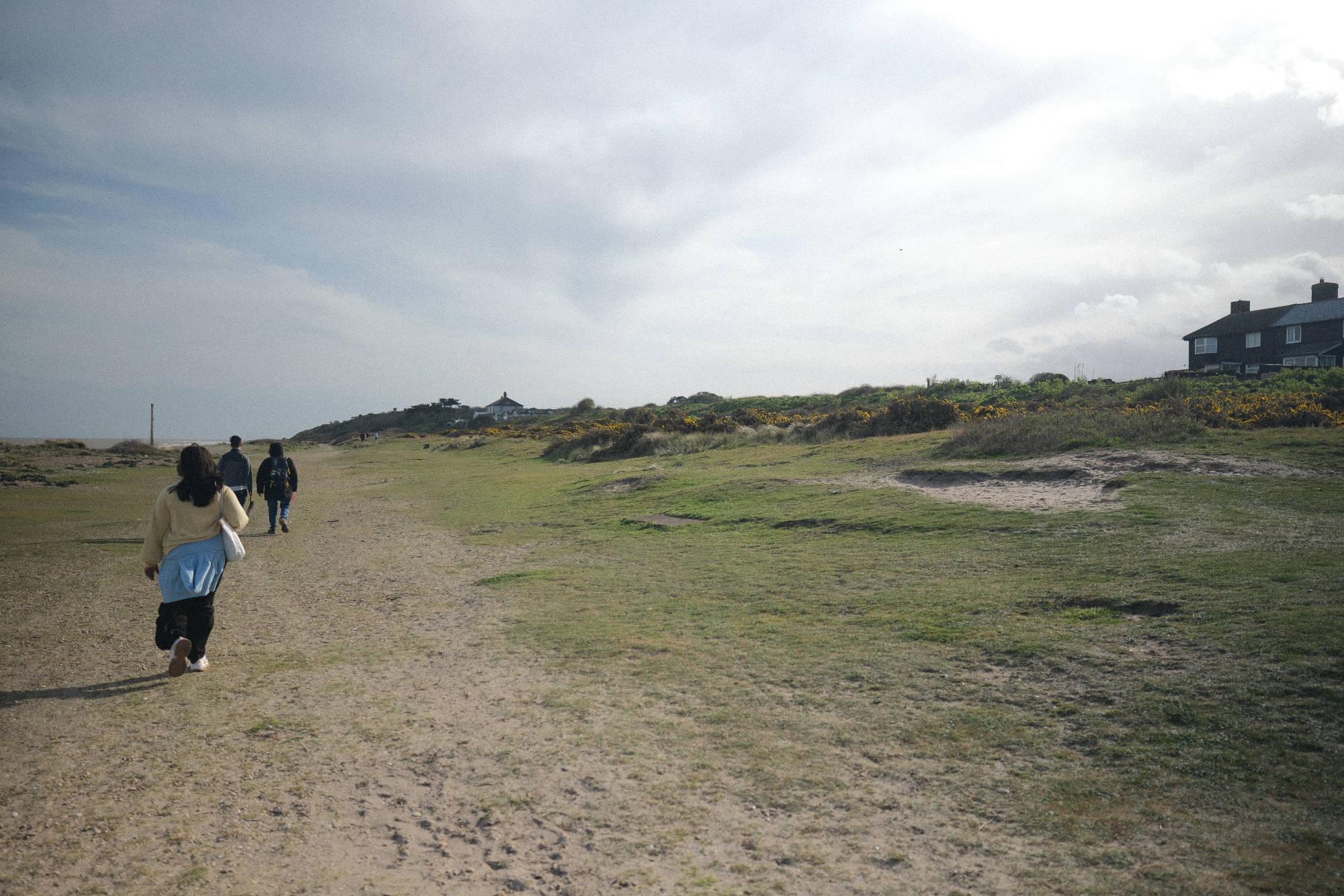 people walking on along a path, with the sea to the left and the sloping shoreline to the right